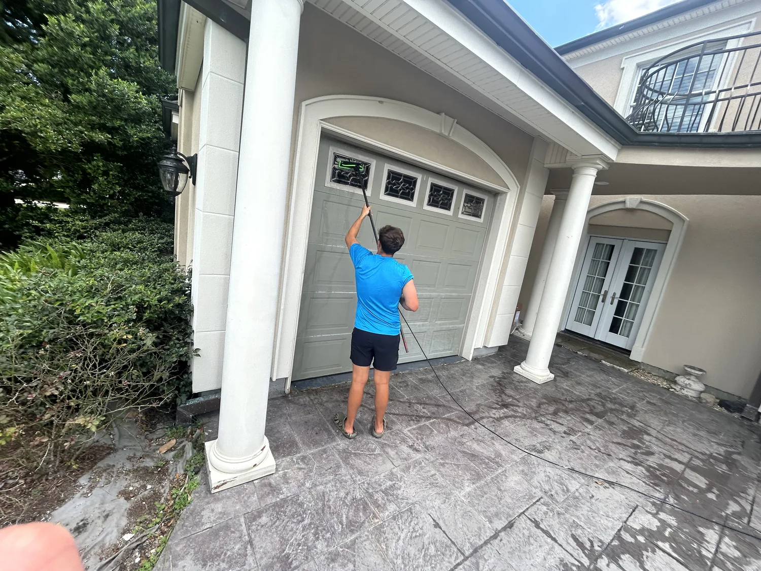 Boot Krewe technician carrying a water fed pole along the side of a house