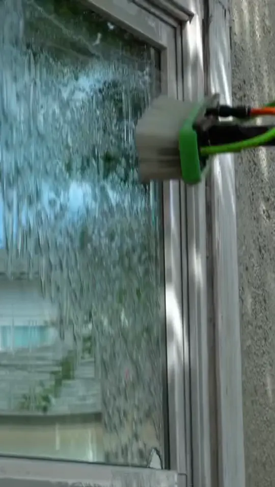 Close view of the soft nylon brush head moving across a window already running with pure water