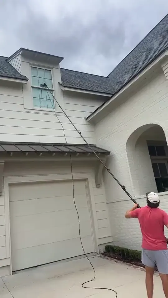 Technician moving along a garage elevation with a water fed pole