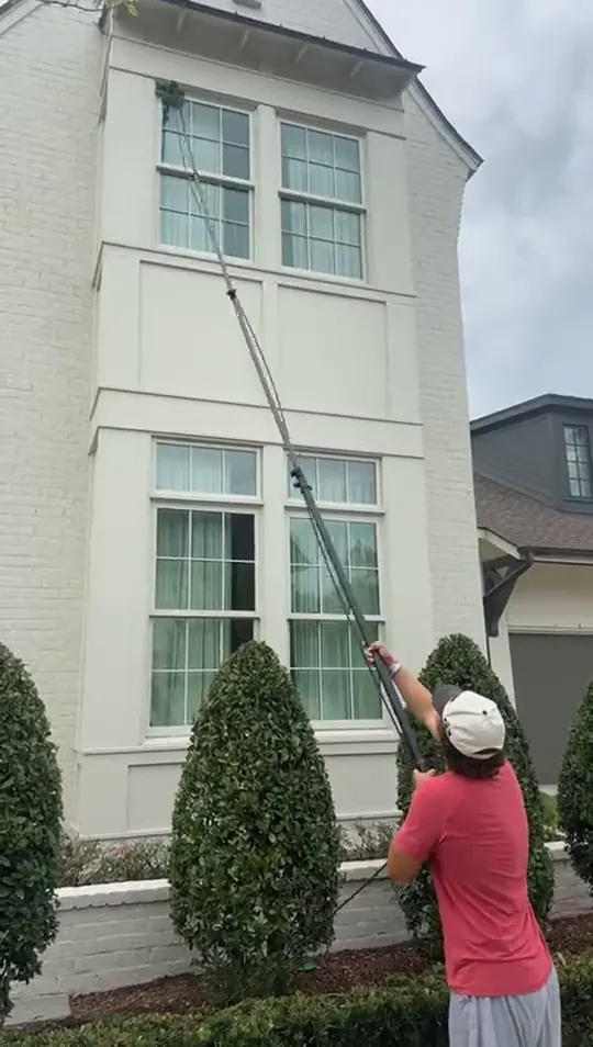 Technician reaching the upper windows of a two storey house with a water fed pole