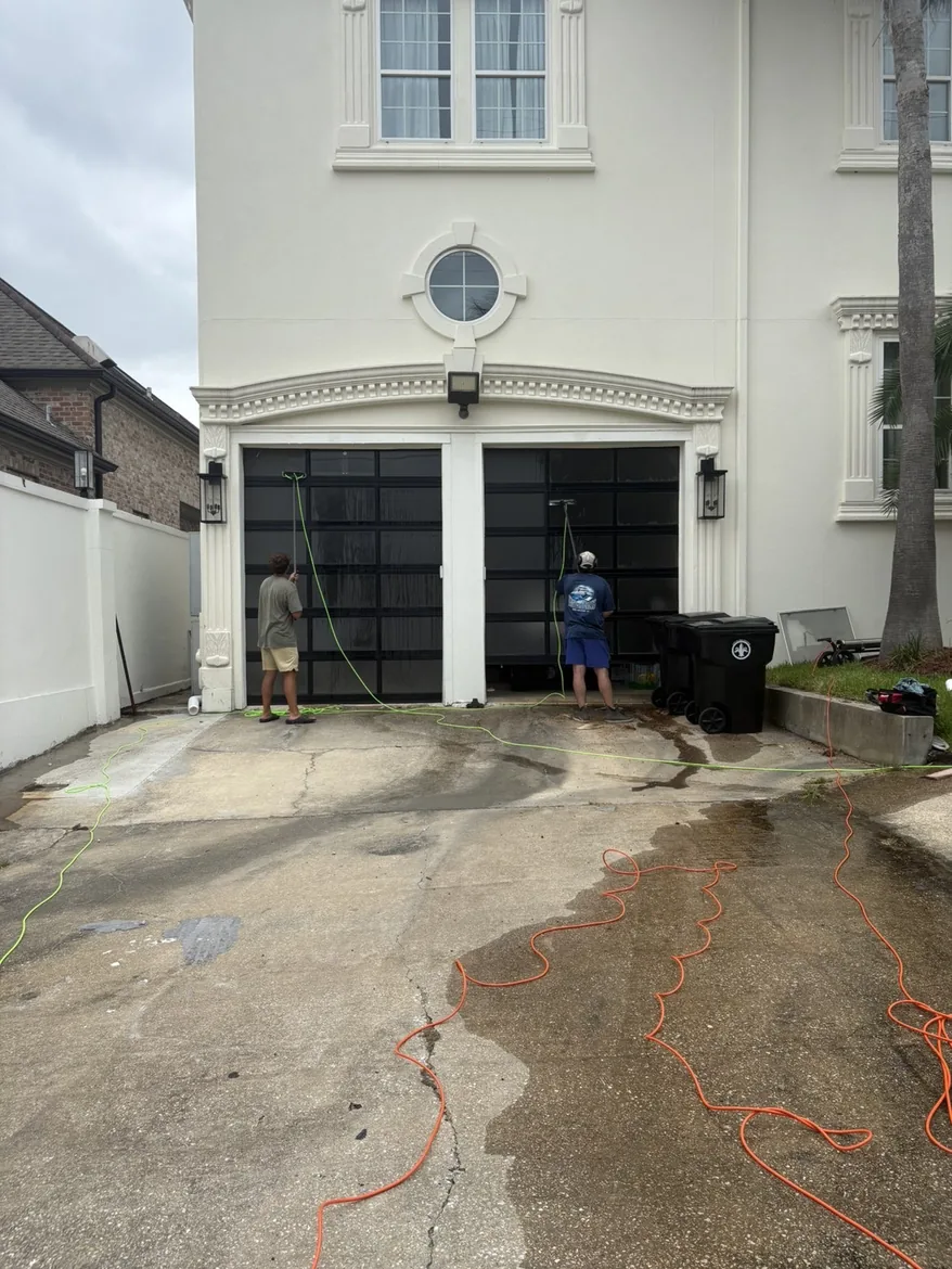 Boot Krewe crew washing a residential driveway, water running across the concrete
